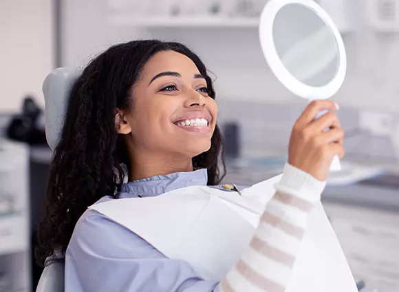 Woman examining her smile in a mirror