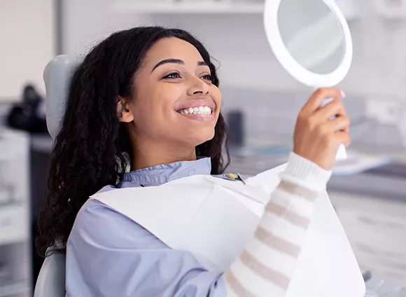 Woman examining her smile in a mirror